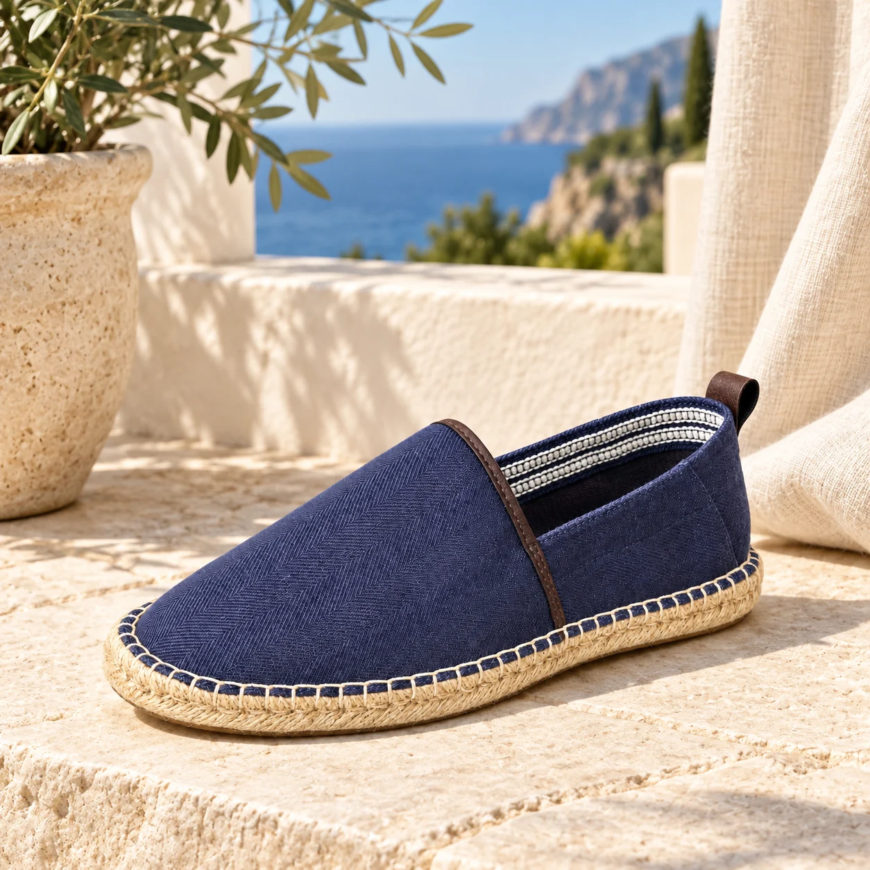 Navy men's espadrille loafer with woven texture and jute-style sole on a sunny coastal terrace